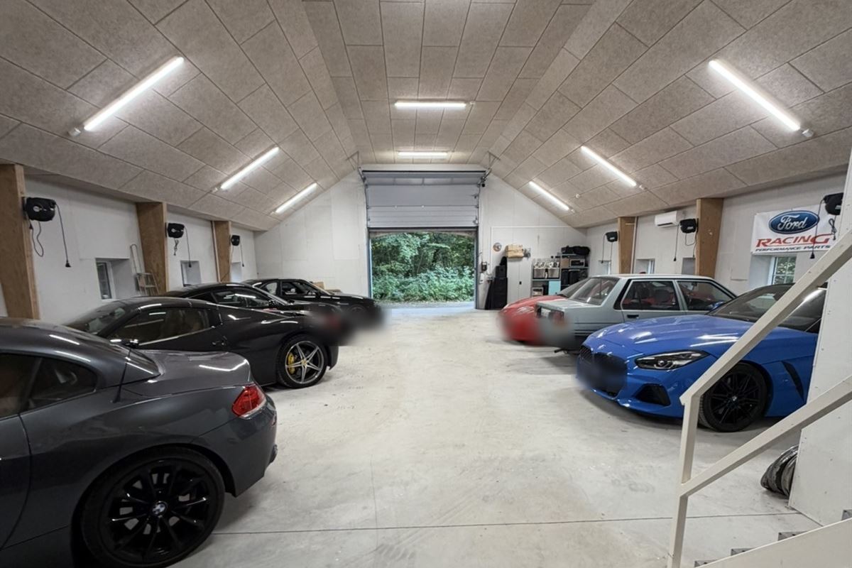 Hallen set mod porten med biler parkeret i to rækker langs væggene